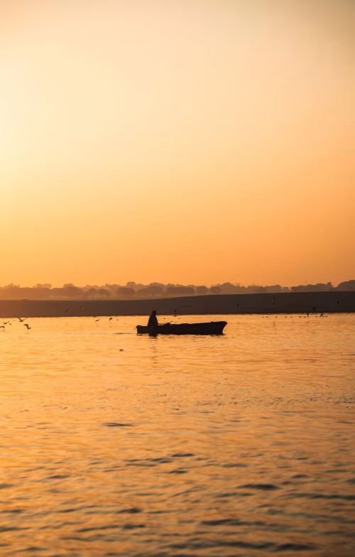 Serene Sunset With Silhouetted Boat on Peaceful River Waters