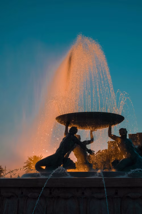 Silhouette of Fountain with Sculptures and Sunset Glow in Background