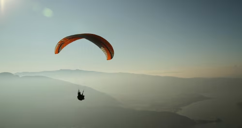 Silhouette of Paraglider Flying Over Scenic Mountains During Sunset