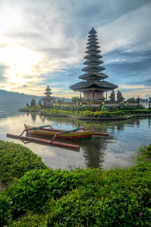 Traditional Balinese Temple on Lake with Wooden Boat and Scenic Sky
