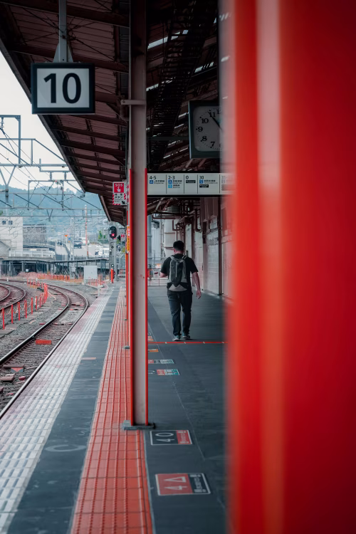 Traveler Walking Along Platform at Train Station With Vibrant Red Accents