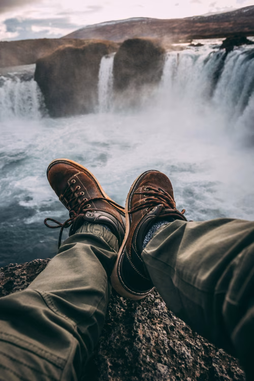 Traveler's Boots Dangling Above a Scenic Waterfall in Stunning Wilderness