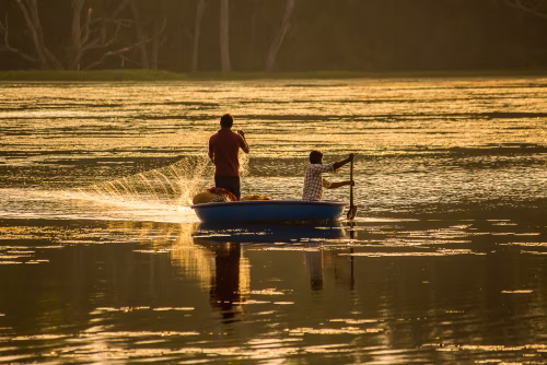 Two People Fishing in a Boat at Golden Sunset on a Serene Lake