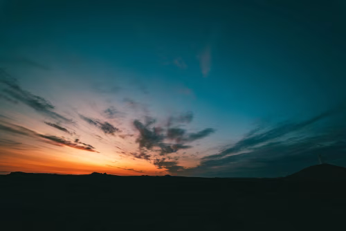 Vast Sunset Sky with Silhouetted Hill and Radiant Colors